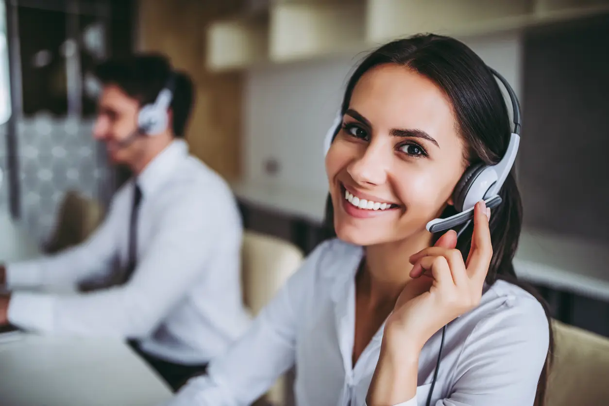 A smiling support agent wearing a headset.